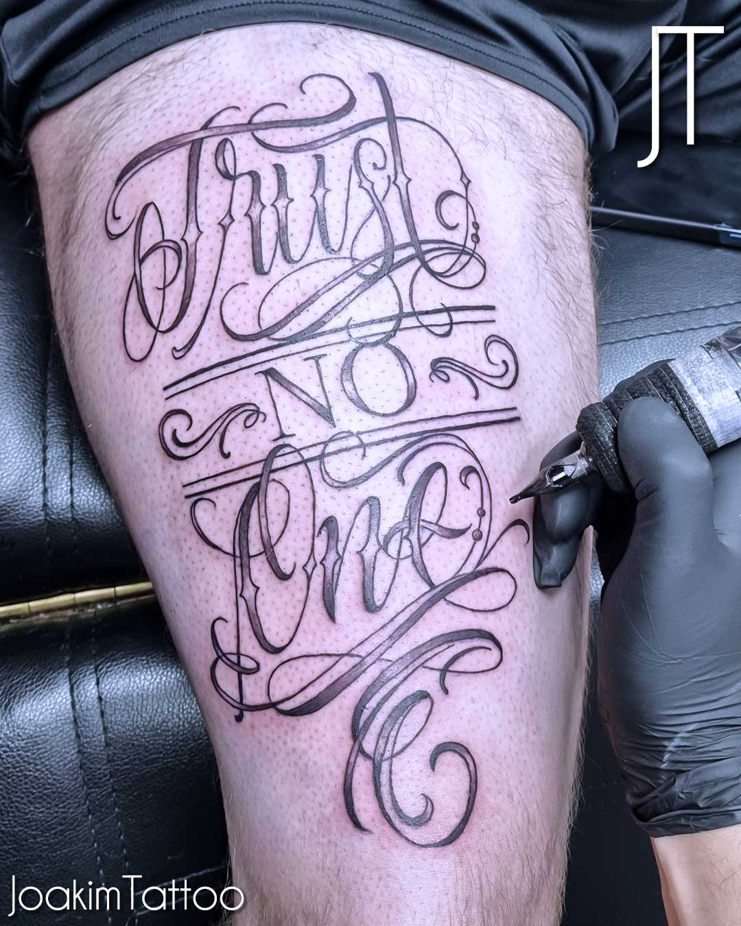 Stor text tatuering på låret Joakim Tattoo i Kungälv