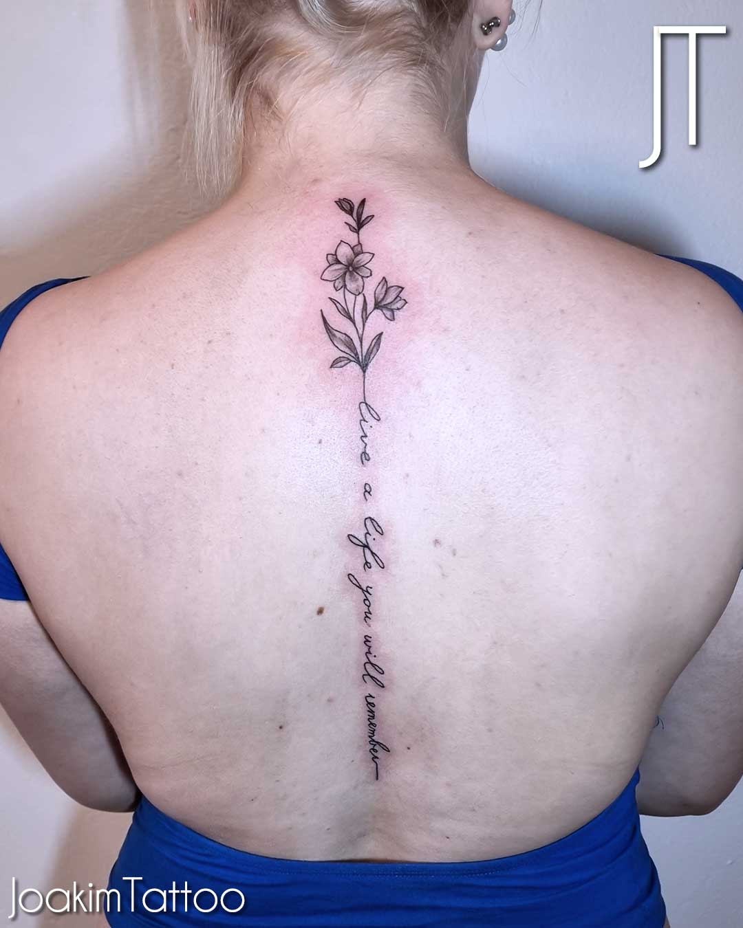 Text tatuering med blomma på ryggraden - Kungälv